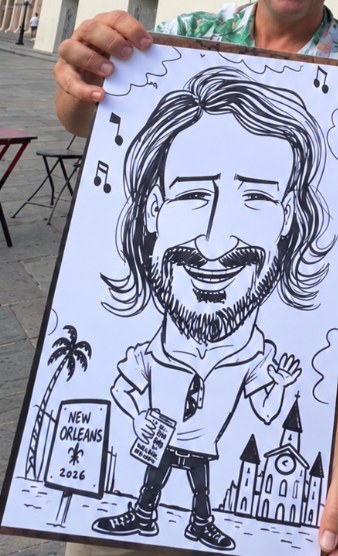 A caricature of me as a reader, drawn on Jackson Square, with a New Orleans 2026 sign and a church in the background
